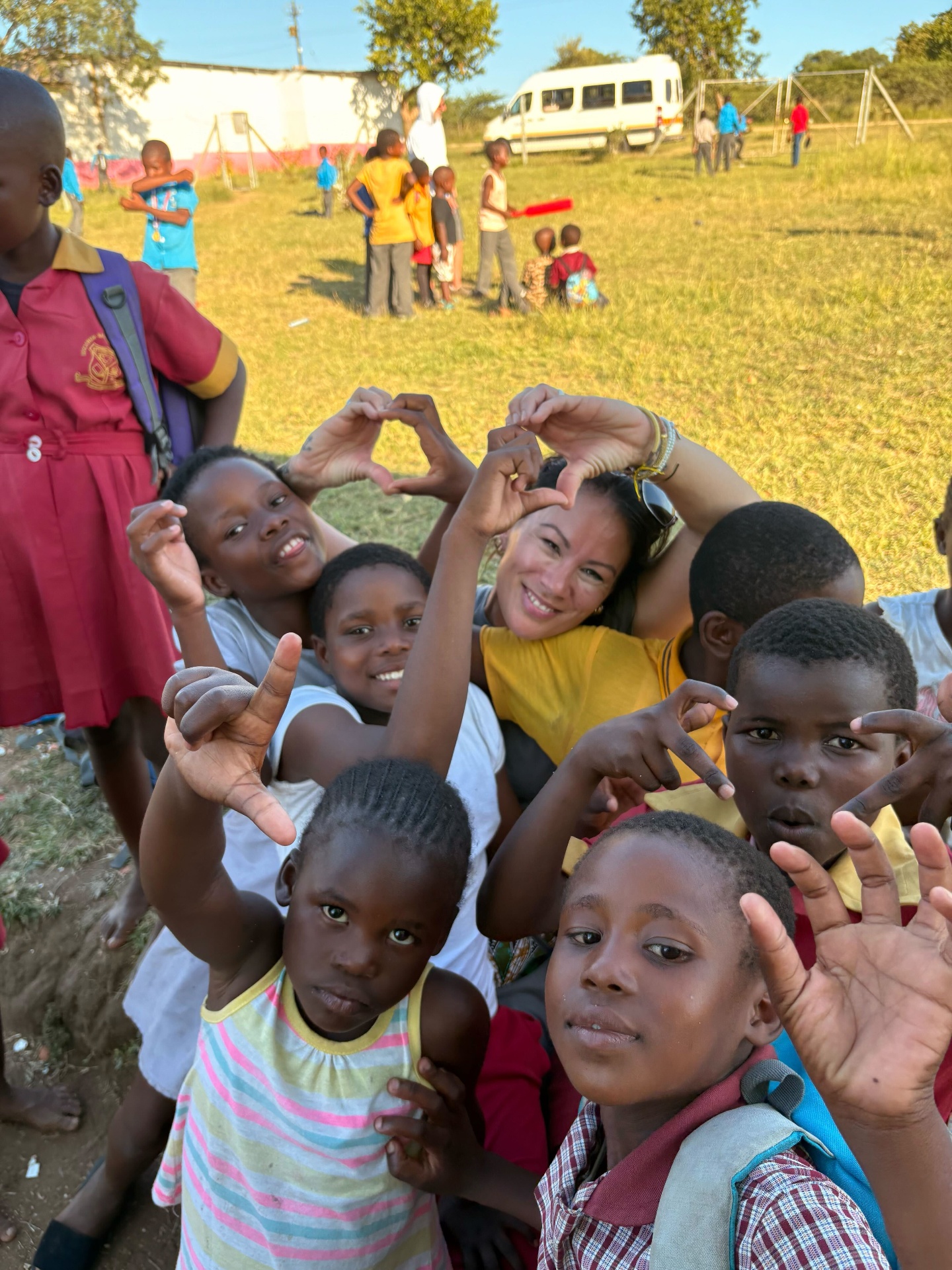 Noelle making heart hands with kids on the field