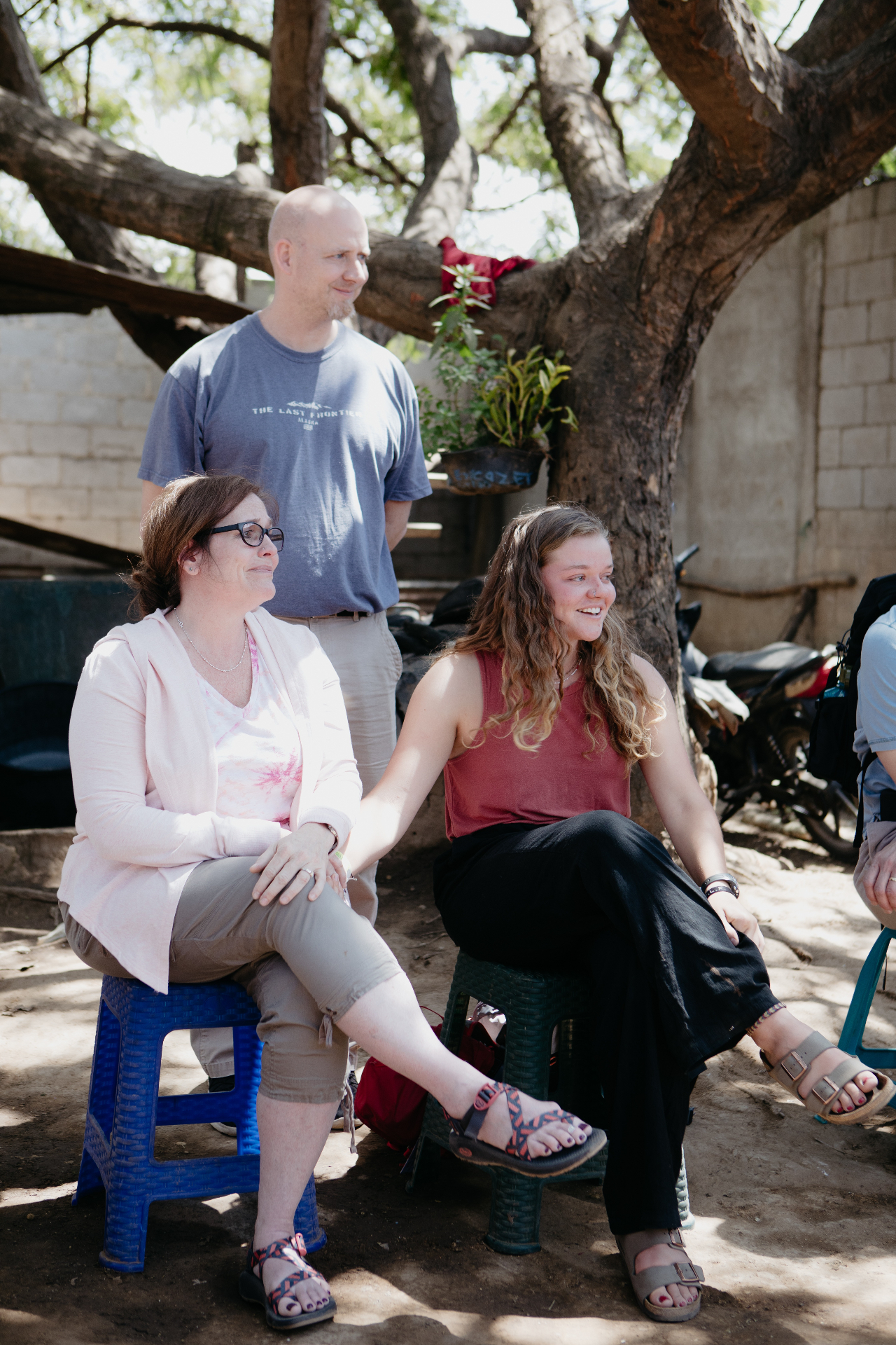 A mom, dad, and Racer daughter sitting under a tree on a Parent Vision Trip
