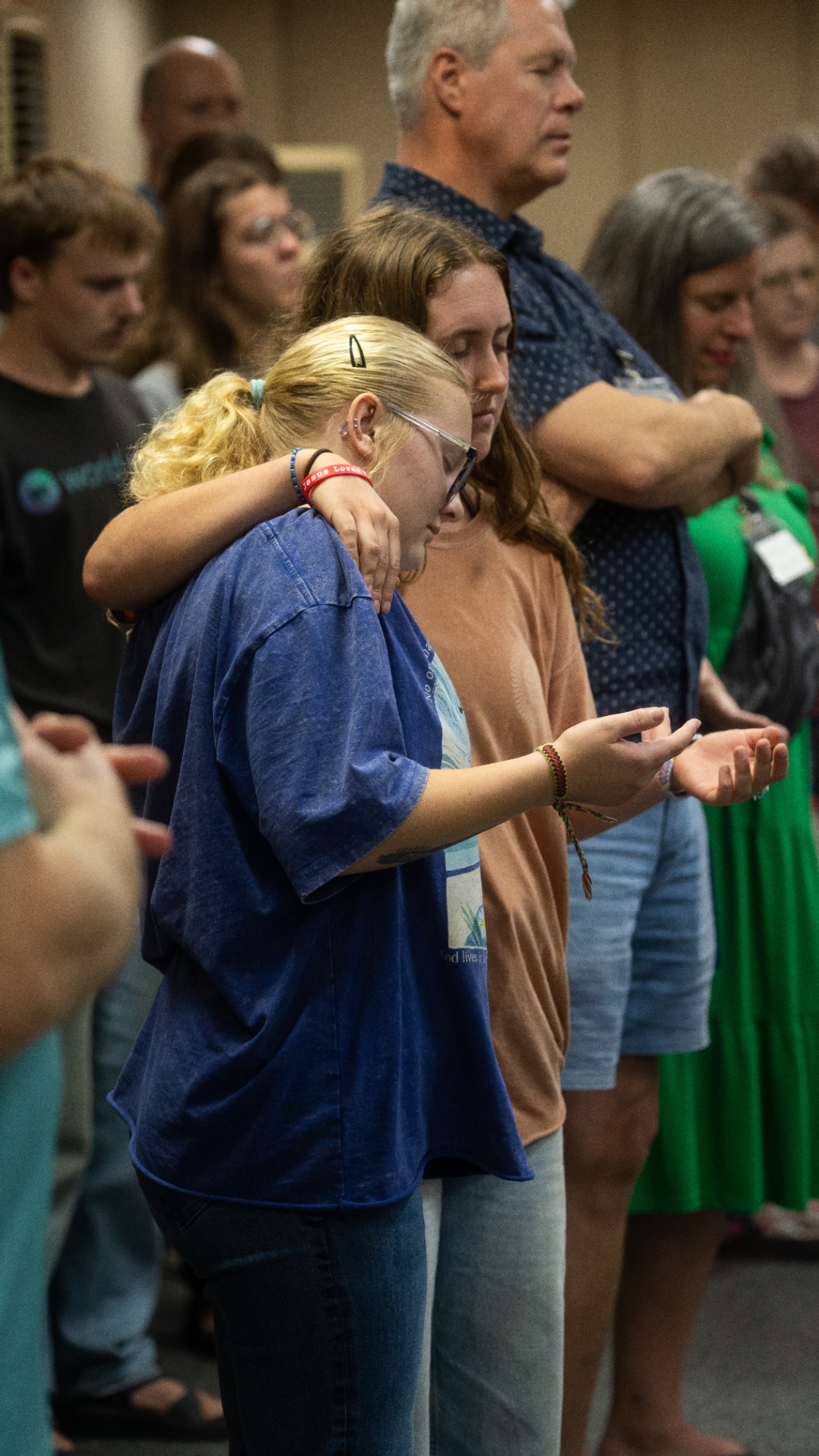 Friends praying together with arms around each other